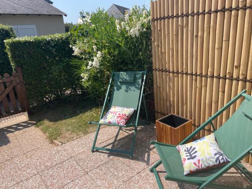 a couple of chairs sitting next to a fence at L'ALOUETTE maison 4/5pers PISCINE/MER Cabourg à pied in Dives-sur-Mer