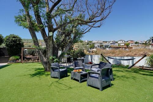 a yard with two chairs and a table and a tree at שלווה במושבה מגדל - וילה מדהימה עם בריכה פרטית וג'קוזי ליד הכנרת in Migdal