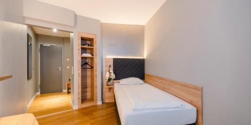 a small bedroom with a bed in a room at PLAZA INN Rieker Stuttgart Hauptbahnhof in Stuttgart
