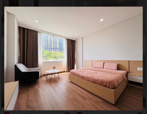 a bedroom with a bed and a chair and a window at Happy House Apartment in Da Nang
