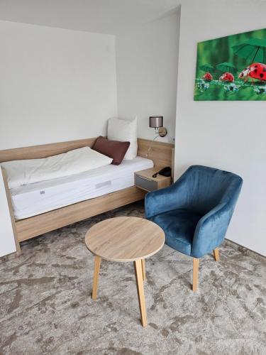 a bedroom with a bed and a blue chair and a table at Hotel Sonnenhof in Bad Waldsee