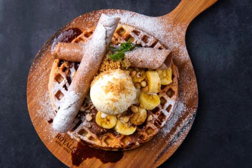 a plate of waffles with eggs and nuts on a wooden spoon at Fiesta Royale Hotel in Accra