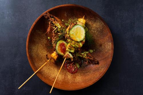 a plate of food on a wooden plate with food at Fiesta Royale Hotel in Accra
