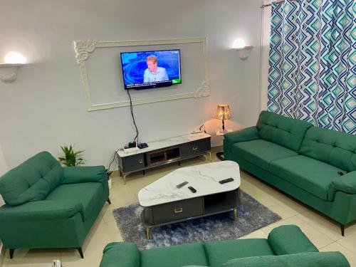 a living room with green couches and a flat screen tv at Chez soi loin de chez soi in Pointe-Noire