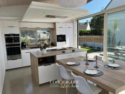 une cuisine avec une table en bois et des armoires blanches dans l'établissement La fauvette, à Barneville-Carteret