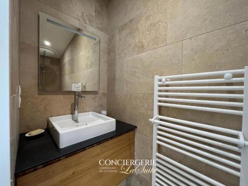 une salle de bain avec un lavabo et un miroir dans l'établissement La fauvette, à Barneville-Carteret