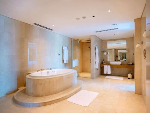 a large bathroom with a tub and a sink at Hilton Doha in Doha