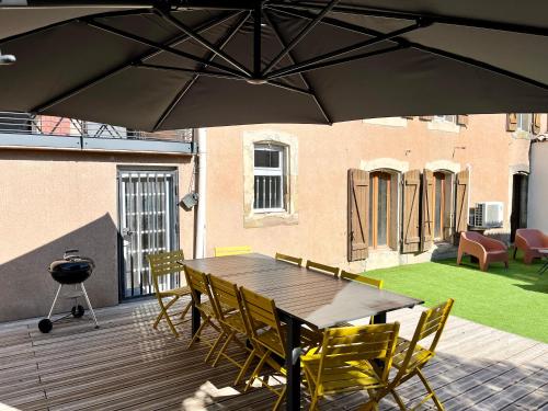a wooden deck with a table and chairs and an umbrella at La circulade - Maison de caractère avec jardin in Bram