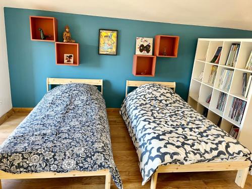 two beds in a room with a blue wall at La circulade - Maison de caractère avec jardin in Bram