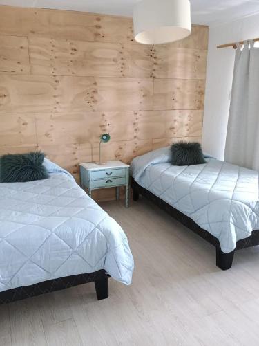a bedroom with two beds and a table with a lamp at Hotel Trocadero in Concón