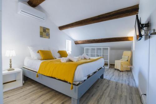 a bedroom with a bed with yellow sheets and wood floors at Gite Grand Luberon chez Manon en Luberon - Vacation rental in guest house in Lagnes