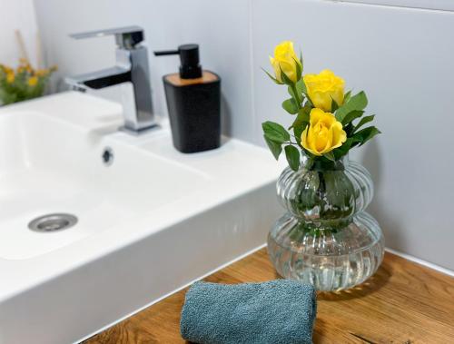 un vaso con fiori gialli appoggiato sul ripiano del bagno di Dream Cottage a Paltin