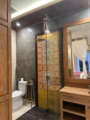 a bathroom with a shower and a toilet and a mirror at Dales Villa in Ubud
