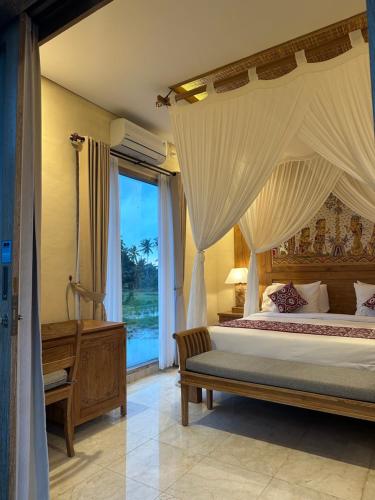 a bedroom with a canopy bed and a window at Dales Villa in Ubud