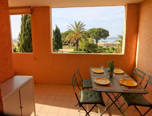 une salle à manger avec une table et des chaises et une fenêtre dans l'établissement Appartement face à la mer avec parking, à La Londe-les-Maures