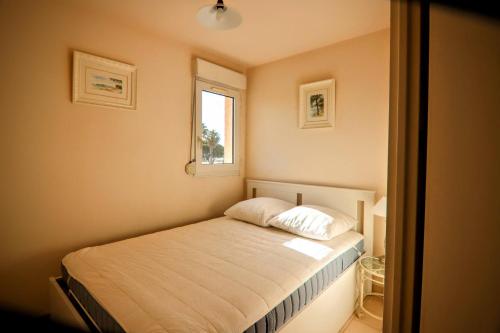 une petite chambre avec un lit et une fenêtre dans l'établissement Appartement face à la mer avec parking, à La Londe-les-Maures