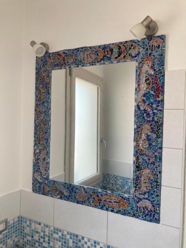 a bathroom mirror with a mosaic border on the wall at Casa mosaico IUN R9770 in SantʼAntìoco