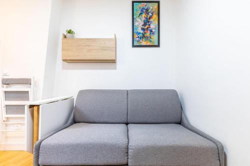 - un canapé gris dans une chambre avec une photo sur le mur dans l'établissement GuestReady - Sérénité au Cœur de Paris, à Paris