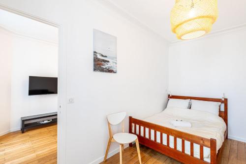 une chambre avec un lit, une télévision et une chaise dans l'établissement GuestReady - Charmant 2 pièces lumineux au calme, à Paris