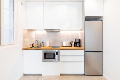  La cuisine est équipée de placards blancs et d'un réfrigérateur. dans l'établissement GuestReady - Charmant 2 pièces lumineux au calme, à Paris