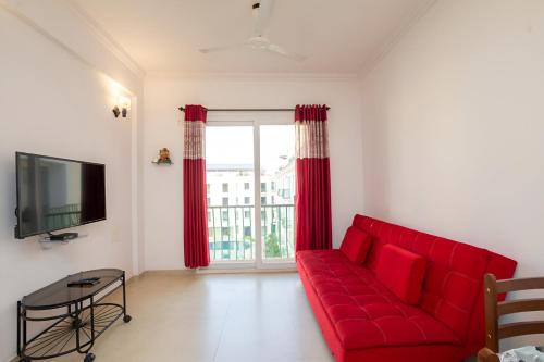 a red couch in a living room with a window at Ronnie's Studio Apartment in Arpora