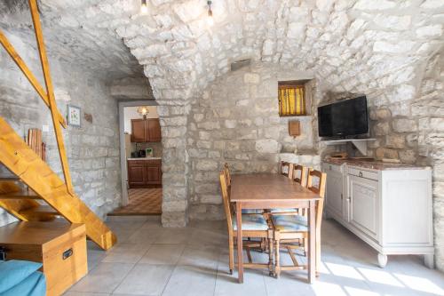 une salle à manger avec une table et un mur en pierre dans l'établissement Gite de l'écurie, à Berrias Et Casteljau