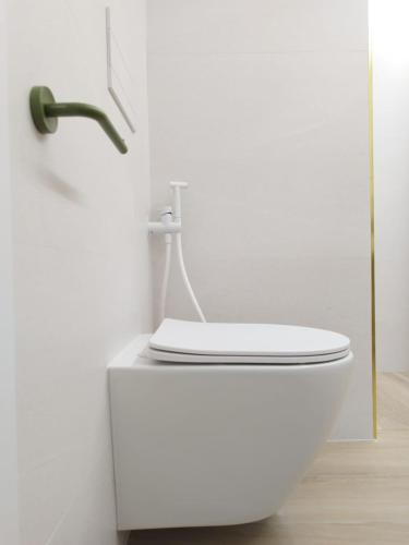 a bathroom with a white toilet in a white wall at Plaza Rooms in Totana