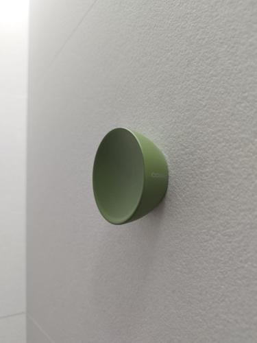 a green pushbutton on a white wall at Plaza Rooms in Totana