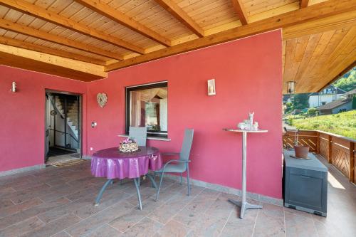 a table and chairs on a patio with a red wall at Ferienwohnung Grimm in Darstein