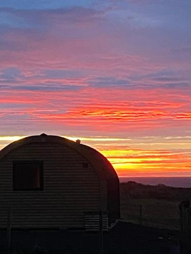 a barn with the sunset in the background at The Glen Lodge in Auckingill