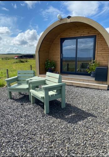 two benches in front of a building with a window at The Glen Lodge in Auckingill