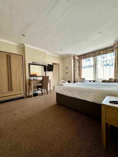a large bedroom with a large bed and a desk at Hotel Coco in Felixstowe