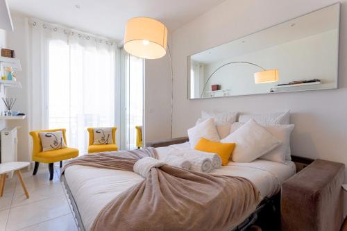 - une chambre dotée d'un lit avec des chaises jaunes et un miroir dans l'établissement Croisette Beach & Palace, à Cannes