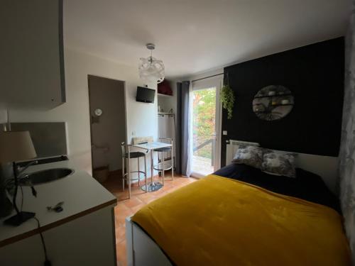 Cet appartement comprend une chambre avec un lit jaune et une cuisine. dans l'établissement escale provençale, au Muy