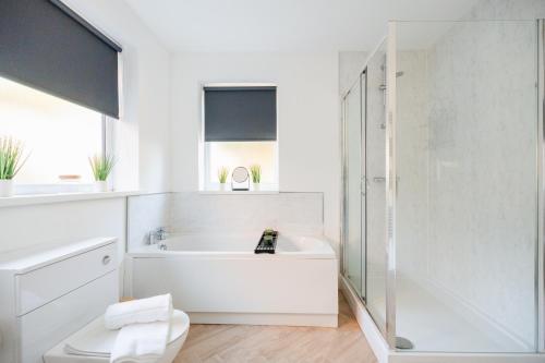 a white bathroom with a tub and a toilet at Rockliffe House By Horizon Stays in Middlesbrough