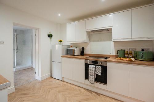 a kitchen with white cabinets and a refrigerator at Rockliffe House By Horizon Stays in Middlesbrough
