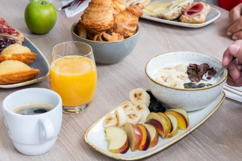 a table topped with plates of breakfast foods and orange juice at ibis Lausanne Centre in Lausanne
