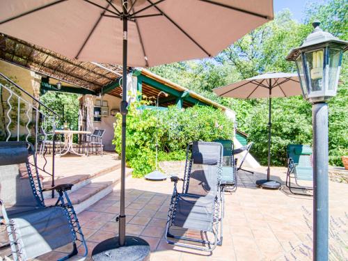 a patio with chairs and an umbrella and a table at Holiday Home La maison aux volets bleus by Interhome in Entrecasteaux