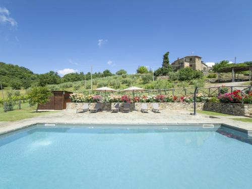 a swimming pool with chairs and a patio with flowers at Holiday Home La Dama by Interhome in Poggioni