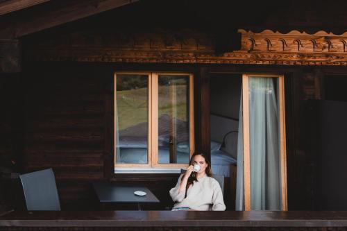a woman sitting in front of a window talking on a cell phone at Bergblick Lodge - 3 Sterne Garni - Neueröffnung in Aeschi