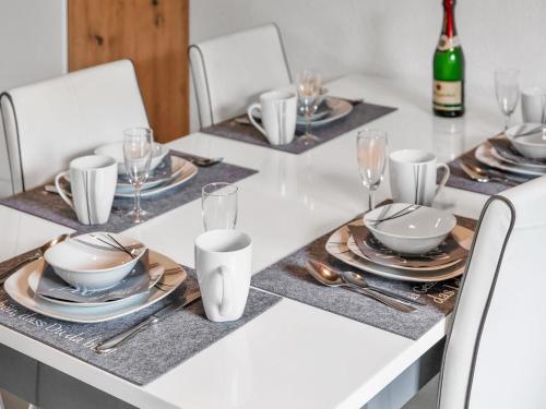a white table with white chairs and plates and wine glasses at Apartment Zum Kreidesee Hemmoor-1 by Interhome in Oberndorf