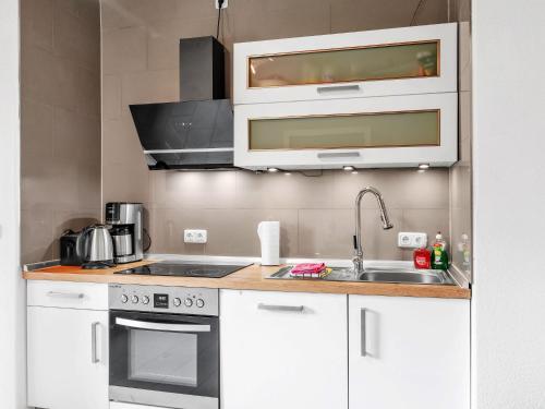 a kitchen with white cabinets and a sink at Apartment Zum Kreidesee Hemmoor-1 by Interhome in Oberndorf