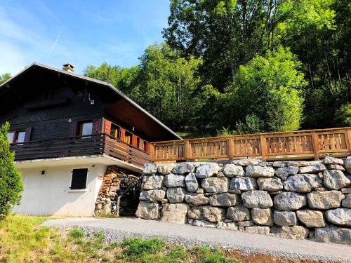 une maison avec un mur en pierre et une clôture dans l'établissement Chalet cosy à Morzine, proche navettes, avec garage, terrasse et équipements complets - FR-1-524-13, à Morzine