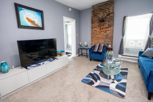 a living room with a flat screen tv and a blue couch at Cozy Haven at the footsteps of Harbor East in Baltimore
