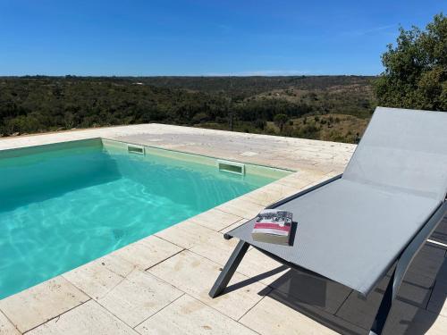 a white chair sitting next to a swimming pool at Casa de Mosqueirões in Santa Margarida da Serra