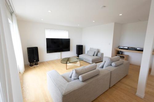 a living room with a couch and a flat screen tv at 熱海の明るい家Saluton in Atami