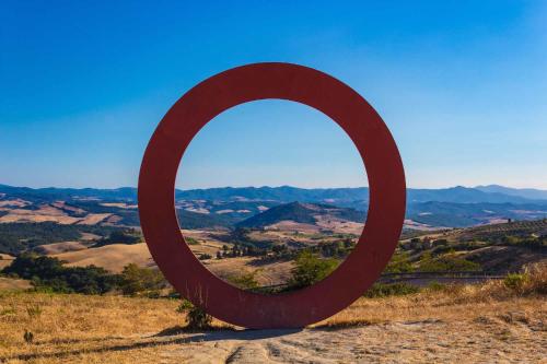a large red circle sculpture on top of a hill at ReginaSerena in Certaldo