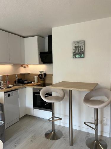 - une cuisine avec une table en bois et deux tabourets de bar dans l'établissement Bel Appartement, à La Croix-Valmer