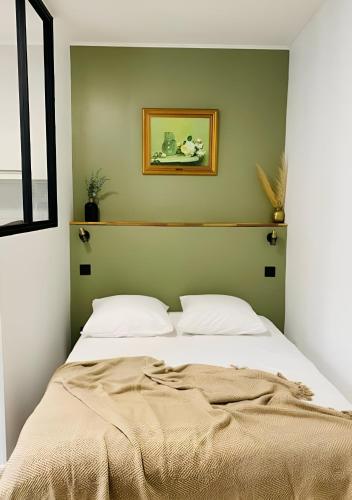 Ce lit se trouve dans une chambre dotée d'un mur vert. dans l'établissement Studio mosaïque Narbonne, à Narbonne