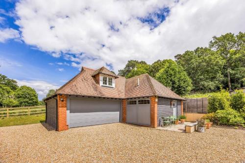 a house with a garage in a gravel driveway at Charming Annexe Lodge with Parking Pass The Keys in Midhurst